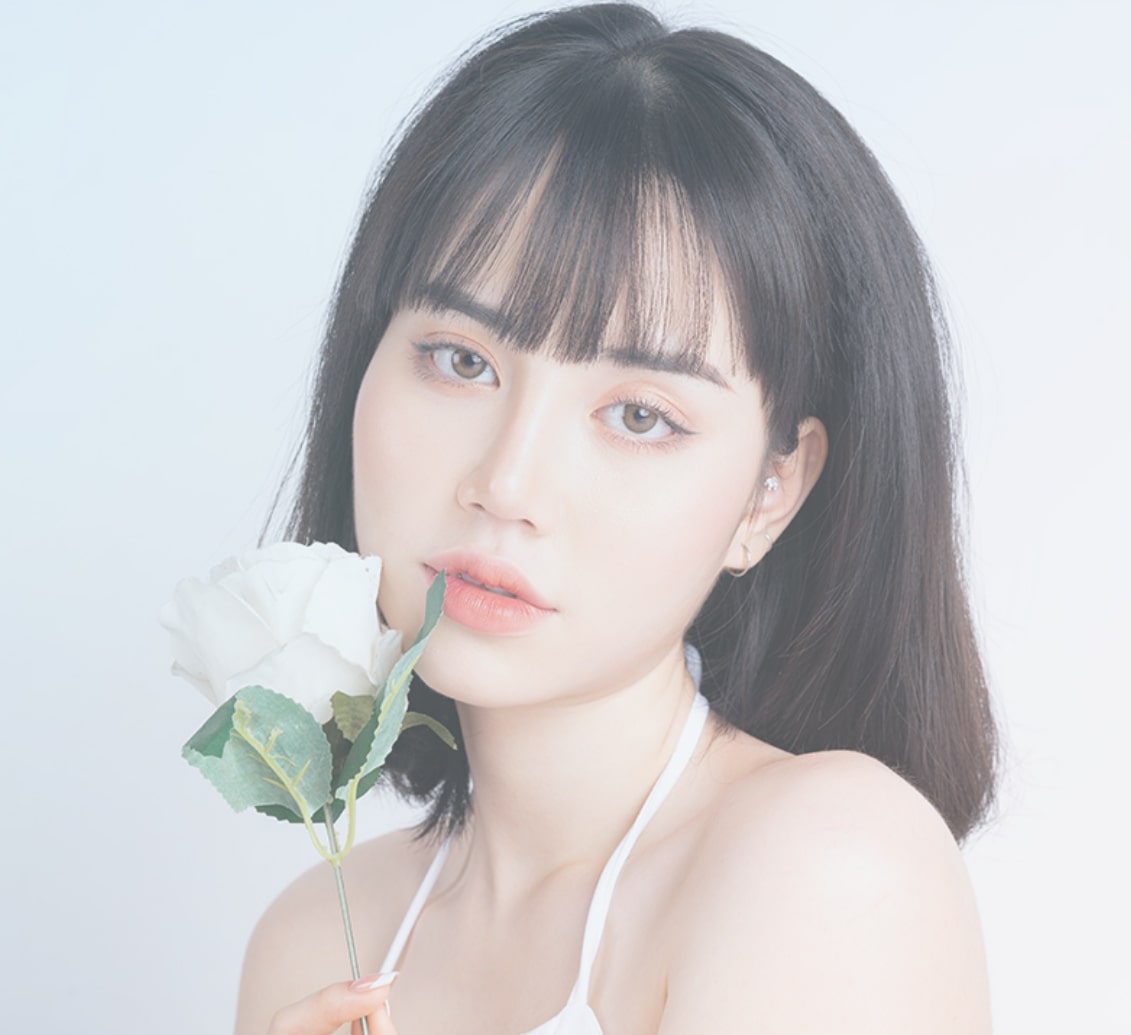 こちらを向き白い花を持った女性モデル